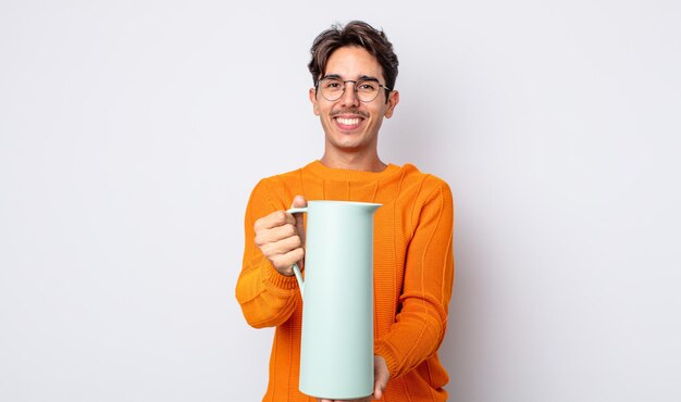 Young hispanic man smiling happily with friendly and  offering and showing a concept. thermos concept