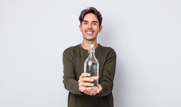 Young hispanic man smiling happily with friendly and  offering and showing a concept. water bottle concept
