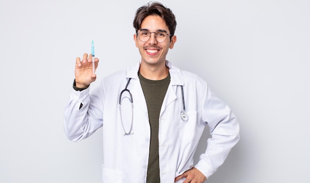 Young hispanic man smiling happily with a hand on hip and confident. doctor syringe concept