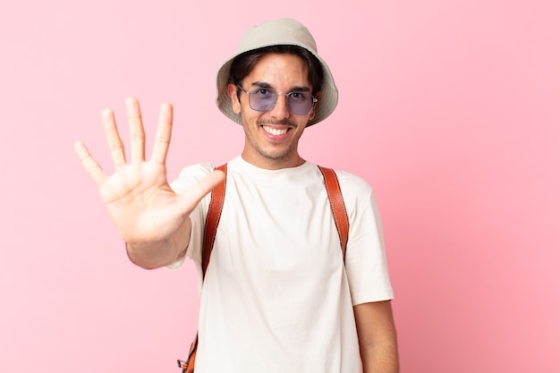 young hispanic man smiling and looking friendly, showing number five. summer concept