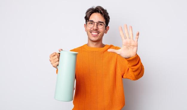 Young hispanic man smiling and looking friendly showing number five thermos concept