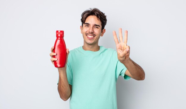 Young hispanic man smiling and looking friendly, showing number three. ketchup concept