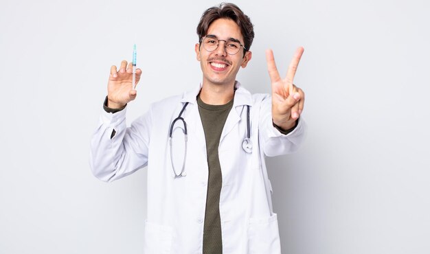 Young hispanic man smiling and looking happy, gesturing victory or peace. doctor syringe concept