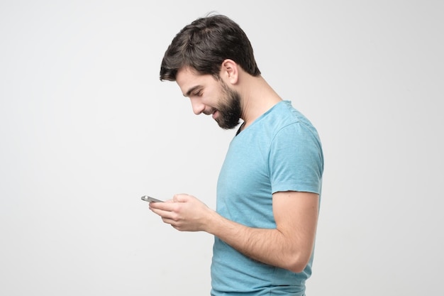 Young hispanic man speaking on the phone and smiling while looking on screen