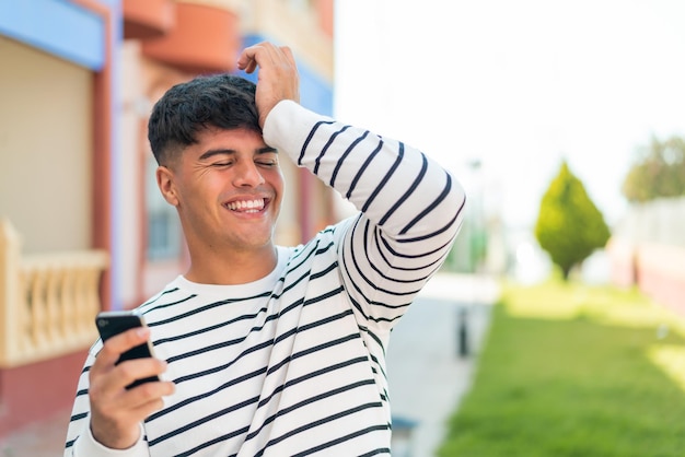 Photo young hispanic man using mobile phone at outdoors has realized something and intending the solution