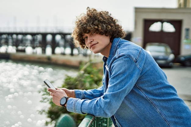 Young hispanic man using smartphone at marina port