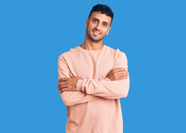 Young hispanic man wearing casual clothes happy face smiling with crossed arms looking at the camera positive person