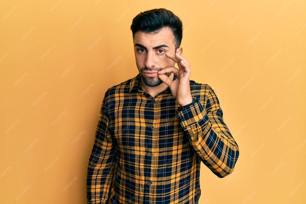 カジュアルな服を着た若いヒスパニック系の男性が、指で口と唇をファスナーで閉じます。秘密で沈黙、タブーな話