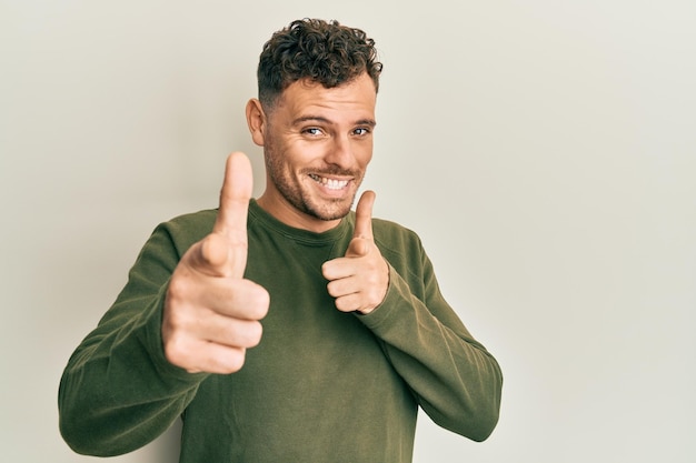 Young hispanic man wearing casual clothes pointing fingers to camera with happy and funny face good energy and vibes