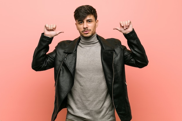 Young hispanic man wearing a leather jacket feels proud and self confident, example to follow.