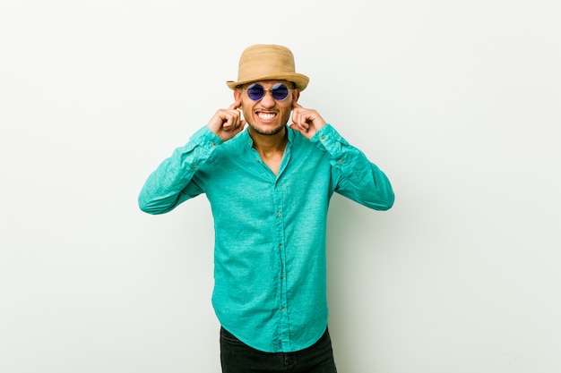 Young hispanic man wearing a summer clothes covering ears with hands.