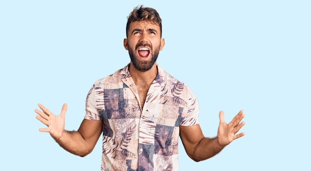 Photo young hispanic man wearing summer clothes crazy and mad shouting and yelling with aggressive expression and arms raised frustration concept