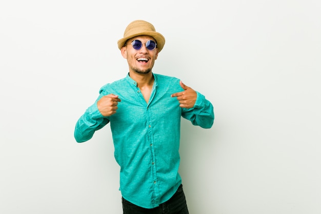 Young hispanic man wearing a summer clothes surprised pointing with finger, smiling broadly.