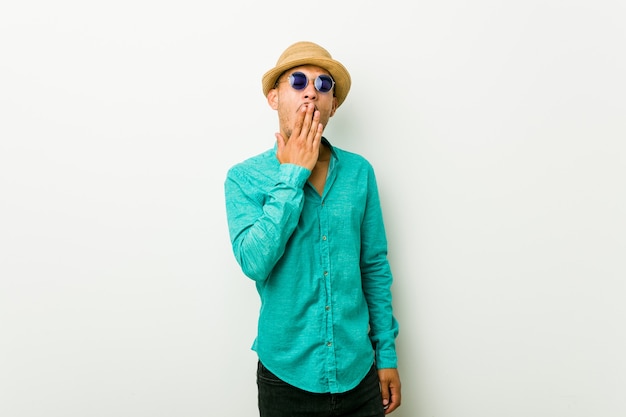 Young hispanic man wearing a summer clothes yawning showing a tired gesture covering mouth with hand.