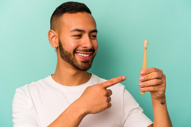Young hispanic man wearing a toothbrush isolated on blue background