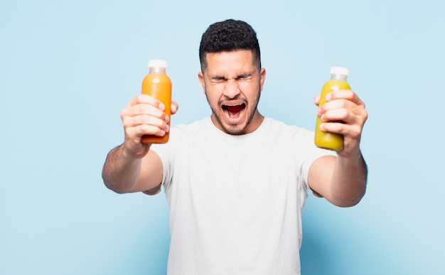 Young hispanic man with angry expression and holding a smoothy