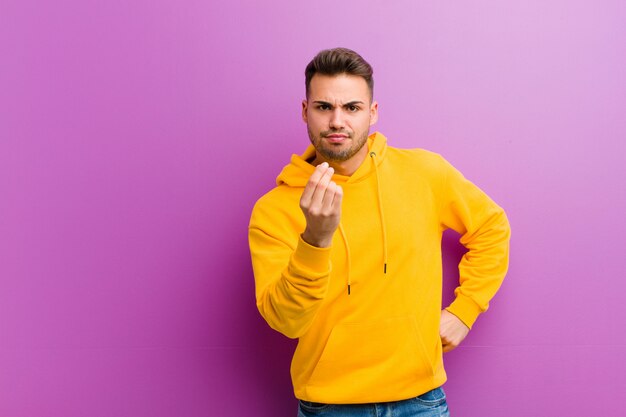 Young hispanic man with casual look against purple background