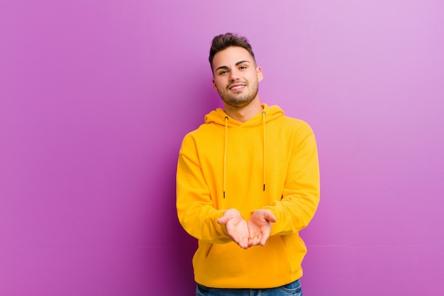 Young hispanic man with casual look against purple wall