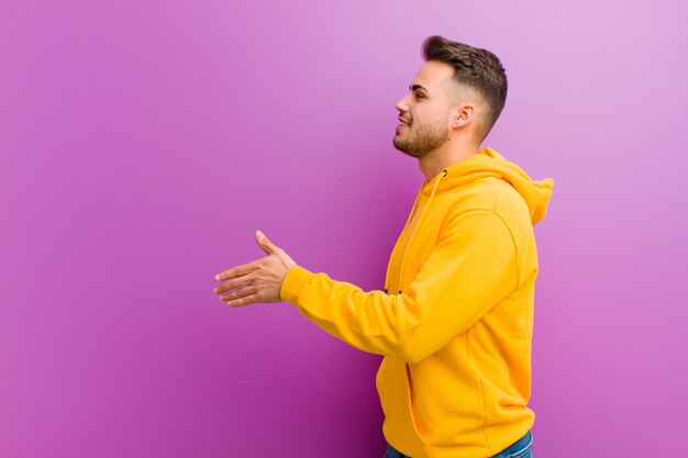 Young hispanic man with casual look against purple wall