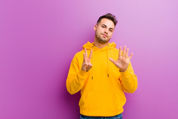 Young hispanic man with casual look against purple wall