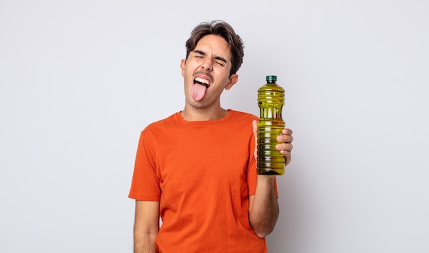 Young hispanic man with cheerful and rebellious attitude, joking and sticking tongue out. olive oil concept