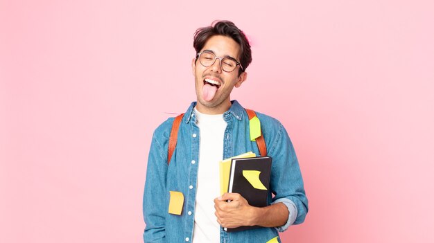 Young hispanic man with cheerful and rebellious attitude, joking and sticking tongue out. student concept