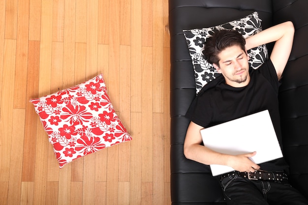 A young hispanic man with a laptop on the Sofa.