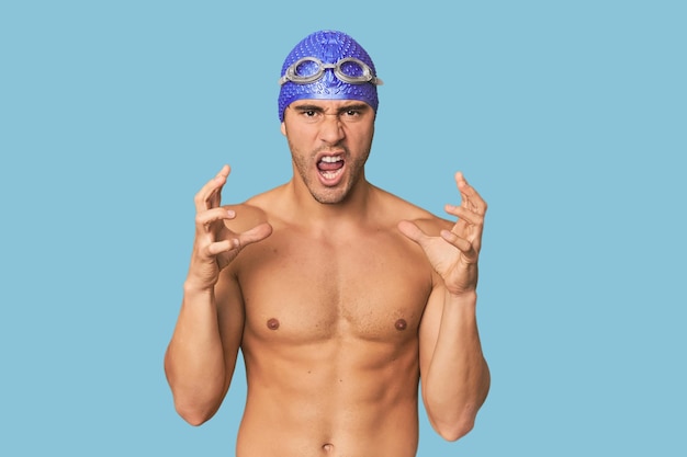 Young Hispanic man with swim gear screaming with rage