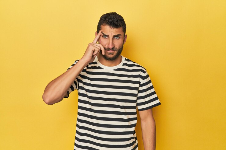 Photo young hispanic man on yellow background pointing temple with finger thinking focused on a task