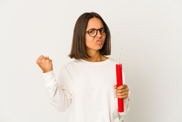 Young hispanic mixed race woman holding a dynamite showing fist to camera, aggressive facial expression.