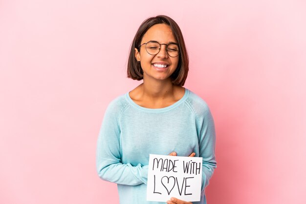 Photo young hispanic mixed race woman holding a made with love paper poster laughing and having fun.