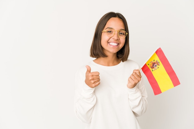 Young hispanic mixed race woman holding a spanish flag smiling and raising thumb up