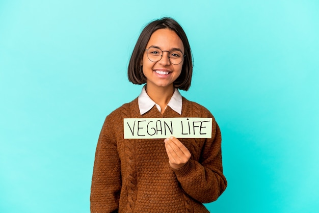 Foto giovane donna ispanica di razza mista che tiene un cartello di vita vegano felice, sorridente e allegro.
