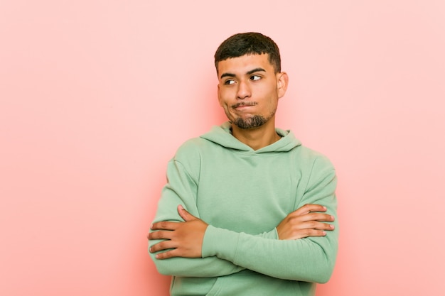 Young hispanic sport man frowning face in displeasure, keeps arms folded.