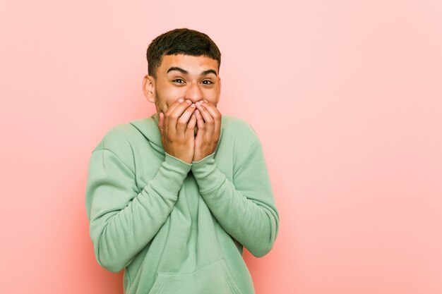 Young hispanic sport man laughing about something, covering mouth with hands