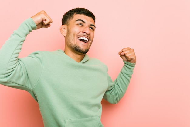 Young hispanic sport man raising fist after a victory, winner concept.