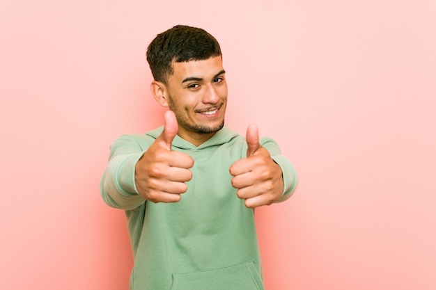 Young hispanic sport man with thumbs ups, cheers about something, support and respect concept.