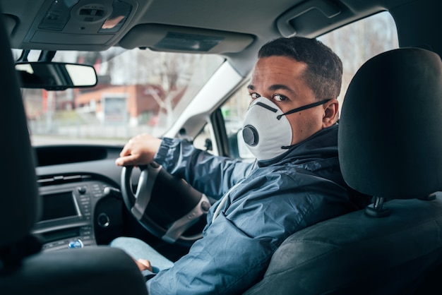 Young hispanic taxi driver wearing a protective mask and talks to a client.