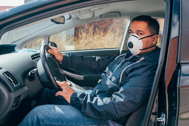 Young hispanic taxi driver wearing a protective mask and waiting for a client. covid 19. coronavirus.