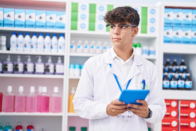 Foto giovane farmacista ispanico dell'adolescente che utilizza il touchpad che lavora in farmacia