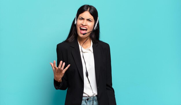 Young hispanic telemarketer woman looking angry, annoyed and frustrated screaming wtf or whatÃ¢ÂÂs wrong with you