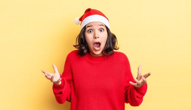 Young hispanic woman amazed, shocked and astonished with an unbelievable surprise. christmas concept