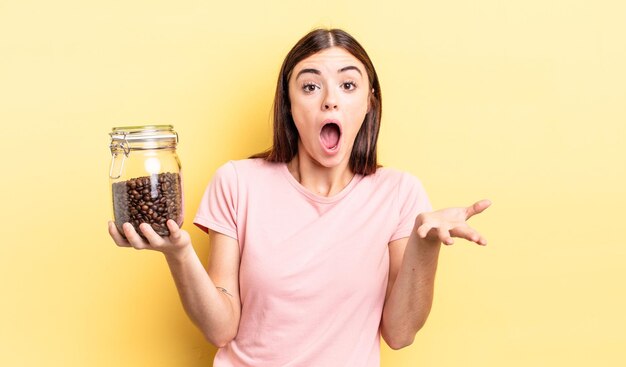 Young hispanic woman amazed, shocked and astonished with an unbelievable surprise. coffee beans concept