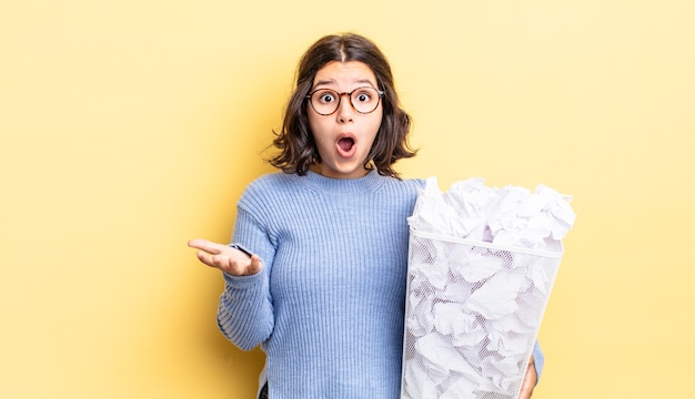 young hispanic woman amazed, shocked and astonished with an unbelievable surprise fail trash concept