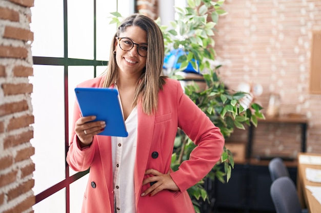 Young hispanic woman business worker using touchpad at office