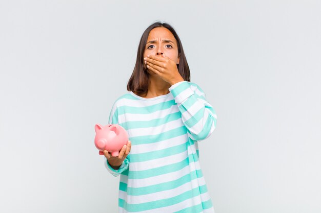 Young hispanic woman covering mouth with hands with a shocked, surprised expression, keeping a secret or saying oops