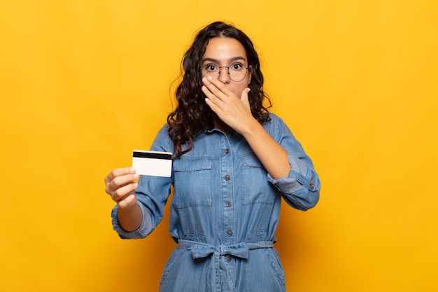 Young hispanic woman covering mouth with hands with a shocked, surprised expression, keeping a secret or saying oops