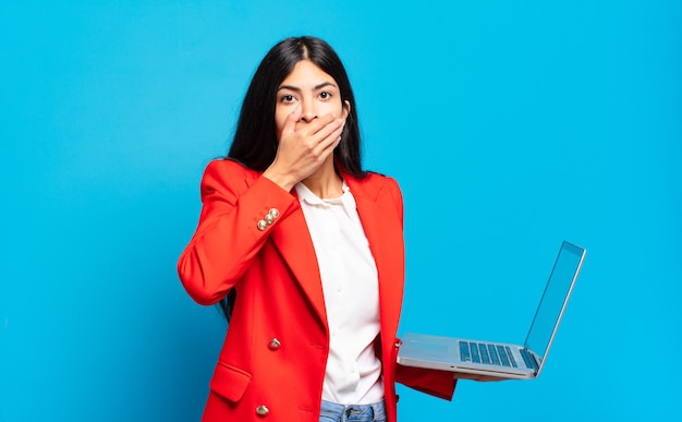 Young hispanic woman covering mouth with hands with a shocked, surprised expression, keeping a secret or saying oops