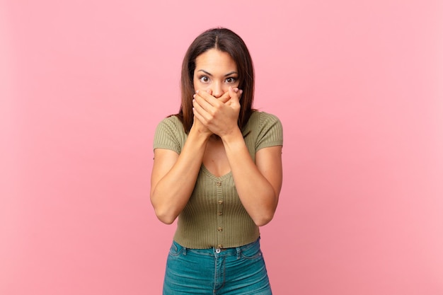 Young hispanic woman covering mouth with hands with a shocked