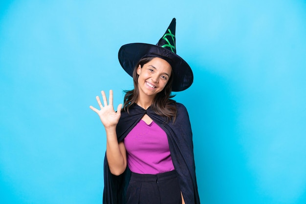 Young hispanic woman dressed as witch over isolated background counting five with fingers